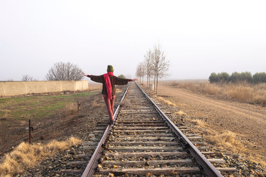Rear view of a girl balancing on train rail while walking