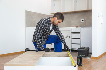 Carpenter measuring shelves that are parts of new kitchen with meter.