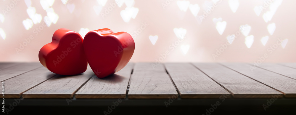 Wall mural 2 beautiful red hearts on a wooden table with hearts background on valentine's day