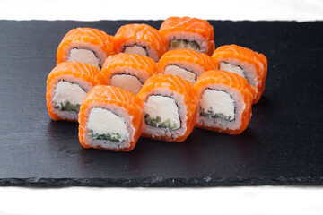 Traditional delicious fresh sushi roll set on a black background with reflection. Sushi roll with rice, cream chees, red fish, salmon. Sushi menu. Japanese kitchen, restaurant. Seafood, asian food