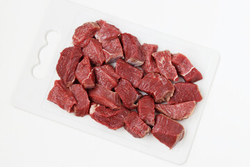 Sliced raw beef on a board isolated on white background. Top view. Horizontal format