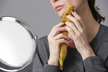 Woman rubbing banana peel on her face to brighten and hydrate skin and reduce wrinkles. Zero waste...