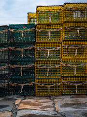 Green and yellow lobster traps stacked on the stone dock
