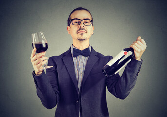 Portrait of a wine expert holding glass of red wine and a bottle