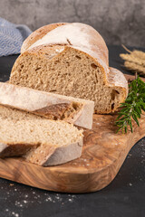 Fresh homemade leavened bread in the sun, partially sliced. Bread is located on a wooden surface. Hobbies, baking rye bread at sourdough at home. Healthy food concept, traditional craft bread. Closeu