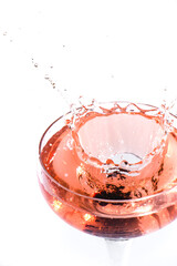 red cocktail splashing in glass on white