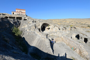 Cave town of Uplistsikhe in Georgia with Uplistsulis Eklesia above. Ruins of city in the rock. Tourists visiting Caucasus.