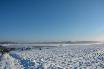 Fototapeta na wymiar Snow landscape with fields and fog and many blue sky