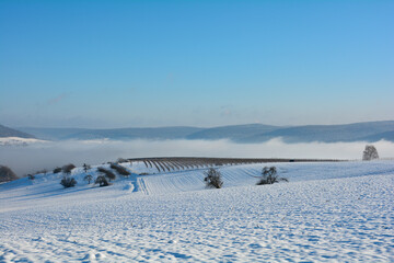 Snow landscape with fields and fog in the valley