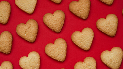 Valentine's Day and Mother's Day banner concept.Pattern of traditional homemade cookies, lots of heart shaped shortbread cookies on red background, top view, flat lay.Festive postcard