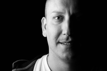 Close-up black and white portrait of a strong, confident male person smiling.