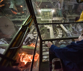 Worker operates in the cabin of a cargo crane at the steel mill