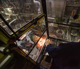 Worker operates in the cabin of a cargo crane at the steel mill