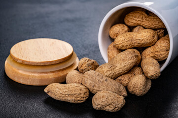 Peanuts on a dark table. Salty snack in a white ceramic container.