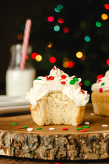 Vanilla cupcake with buttercream icing and christmas colored sprinkles on a wooden table