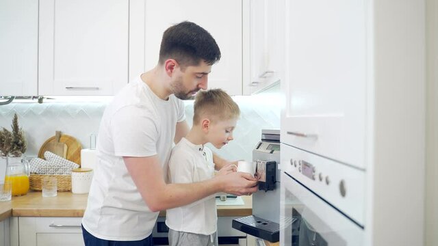 Father and son make coffee in the morning at home in the kitchen. dad together with the child prepare a hot drink in a coffee machine. A happy family parenting.