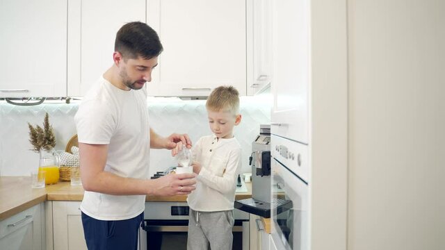 Father and son make coffee in the morning at home in the kitchen. dad together with the child prepare a hot drink in a coffee machine. A happy family parenting.