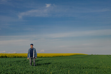 Fototapeta na wymiar Portrait of Successful Farmer Examining Crops at Agriculture Field. Farmer Looking at Crops Wheat Field