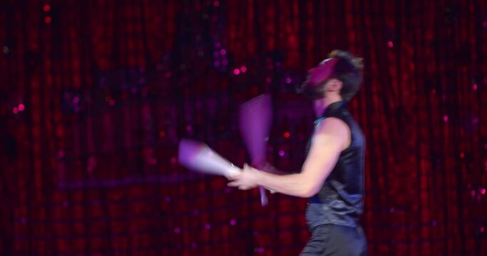 Professional juggler is performing on stage of a circus, juggling maces, 4k