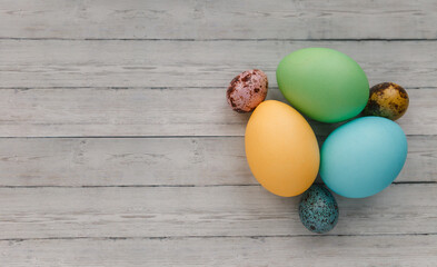 Many colorful painted Easter eggs on light wooden background, top view. Space for text