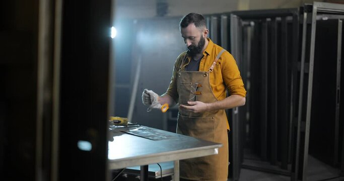 Portrait of a handsome welder, taking off his gloves, going to have a coffee break at the factory