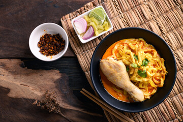 Northern Thai food (Khao Soi), Spicy curry noodles soup with chicken eating with crispy deep-fried egg noodles, pickled mustard, shallots, lime and ground chilies in oil