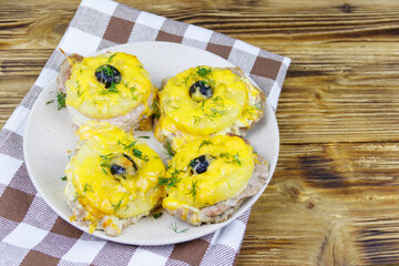Pieces of baked pork with pineapple, cheese and olive on a wooden table
