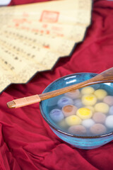 A bowl of dumplings and traditional folding fans on a red cloth background