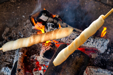 Barbecue with fresh bread on wooden sticks, Stockbrot (stick bread).