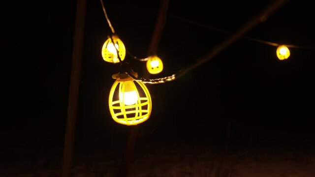 Slow motion shot of work light string swinging in snow storm