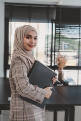 Fototapeta premium Professional arab businesswoman brown hijab standing and holding a financial investment project report. indoor