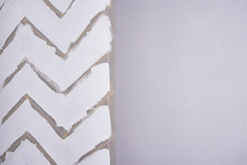 Painting a wall with masking tape. white zigzag strips on grey wall.