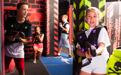 Obraz na płótnie Canvas Group of happy teenagers with laser guns having fun on dark lasertag arena..