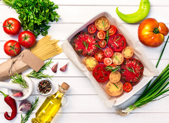 Fresh organic ingridients, pasta spaghetti of italian recipes. Tomatoes with rosemary into ceramic. Healthy food concept on white wooden table background. Top view, copy space