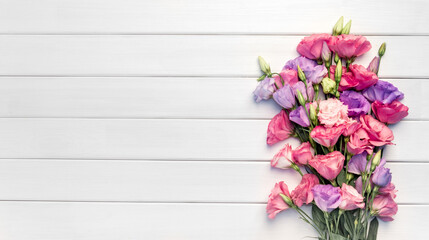 Beautiful bouquet of eustoma flowers on white wooden background. Copy space, top view,