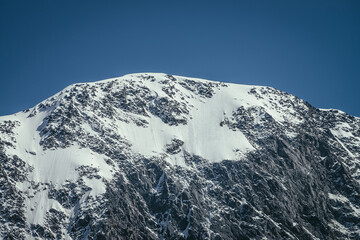 Awesome mountains landscape with black white snowy mountain top in sunny blue sky. Minimalist...