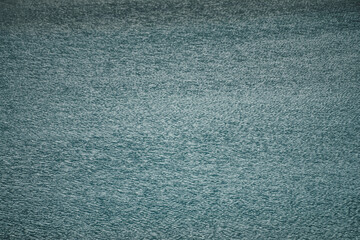 Texture of dark blue calm water of lake. Meditative ripples on water surface. Nature minimal background of deep blue lake. Natural backdrop of clear dark turquoise water. Full frame of lake fragment.