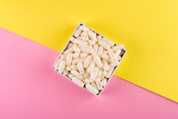 White pills isolated on pastel coloured background. Medication and prescription pills flat lay background.