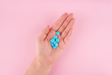 Hands hold blue pills isolated on pastel coloured background. Medication and prescription pills flat lay background.