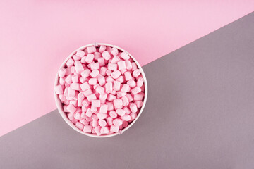 Colorful marshmallow laid out on pink and gray paper background. pastel creative textured pattern. minimal style.
