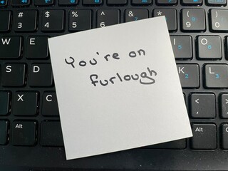 A handwritten note on a computer keyboard stating you’re on furlough. Furlough is a leave of...