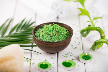 Spa. Green herbal spirulina salt in ceramic bowl, spa towels, candles and bamboo