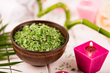 Spa. Green herbal spirulina salt in ceramic bowl, spa towels, pink scented candle and bamboo