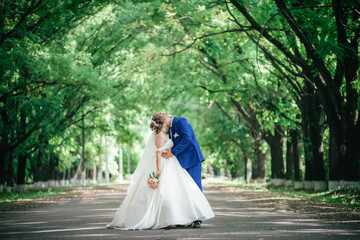 Wedding, couple of bride and groom kissing in park with very big trees
