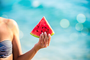 Watermelon slice in woman hand over sea - POV. Summer beach concept. Tropical fruit diet.