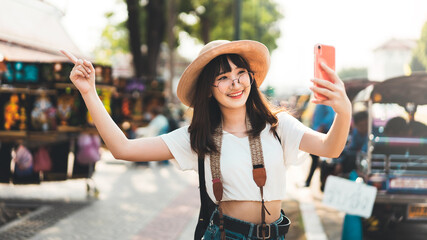 Young adult tourist asian woman using smart phone for selfie with temple background at outdoor on day