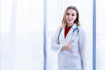 young female doctor therapeutic advising with positive emotions showing thumbs up with smiley face very good on wooden table in Hospital background