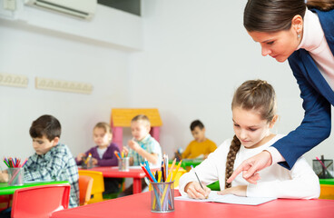 Young female teacher working with pupils in classroom at elementary school