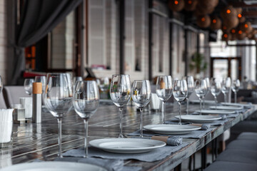 Modern veranda restaurant interior, banquet setting, glasses, plates