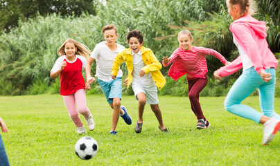 Obraz na płótnie Canvas Company of children playing football on the playground in park